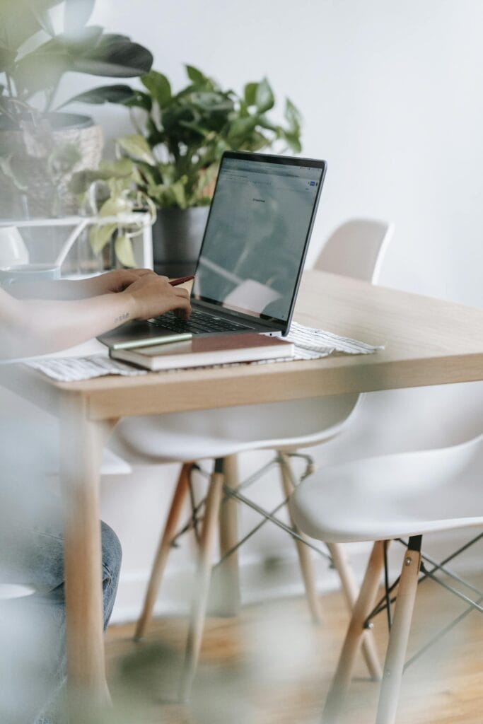 Unrecognizable worker typing on laptop at table with flowers
